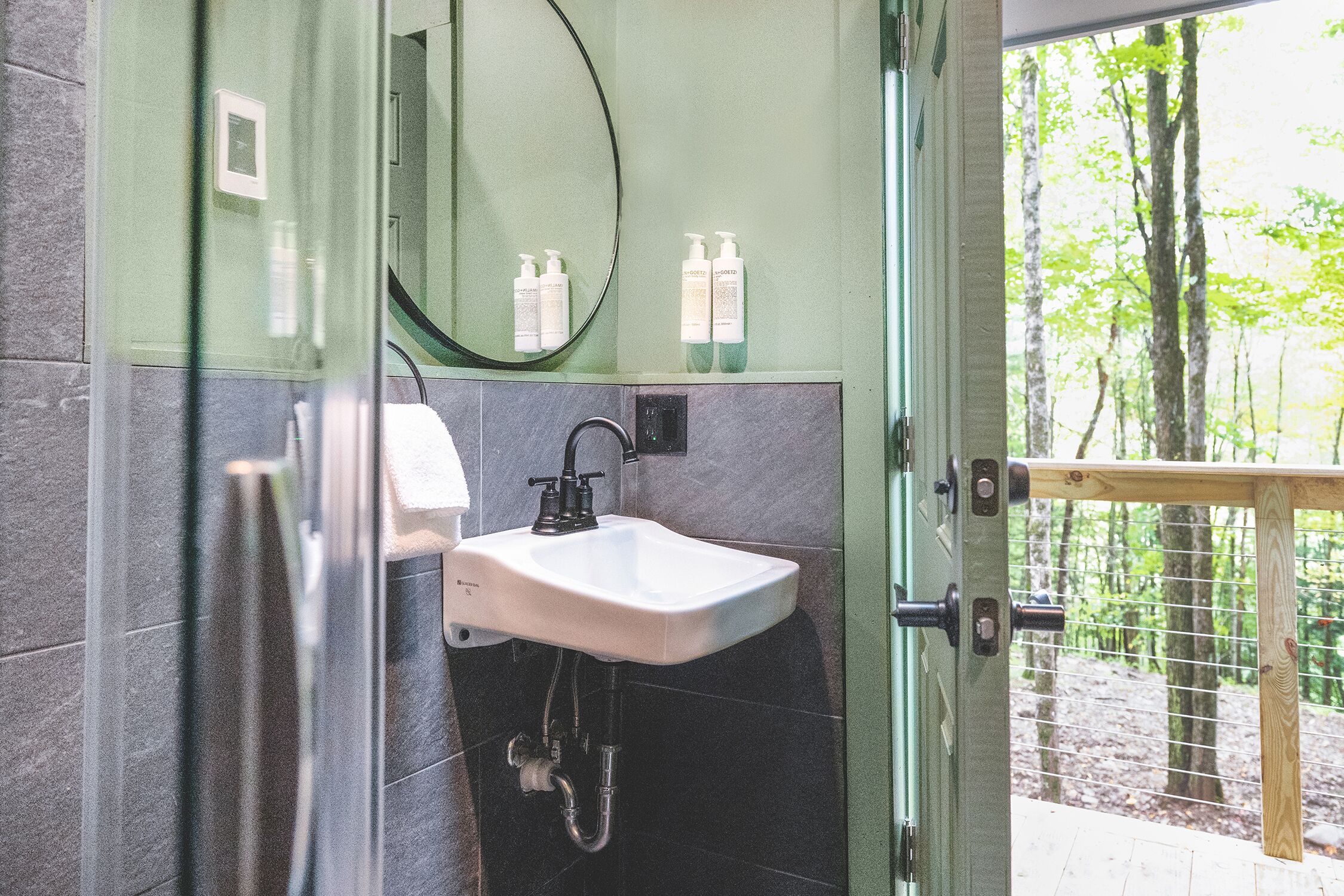 A bathroom with a white sink, a mirror, and toiletries on the wall.