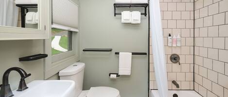 A bathroom with a toilet, sink, and shower. There are towels and toiletries visible.