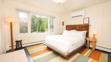 A bedroom with a bed, a window, a bedside table, and a floor lamp.
