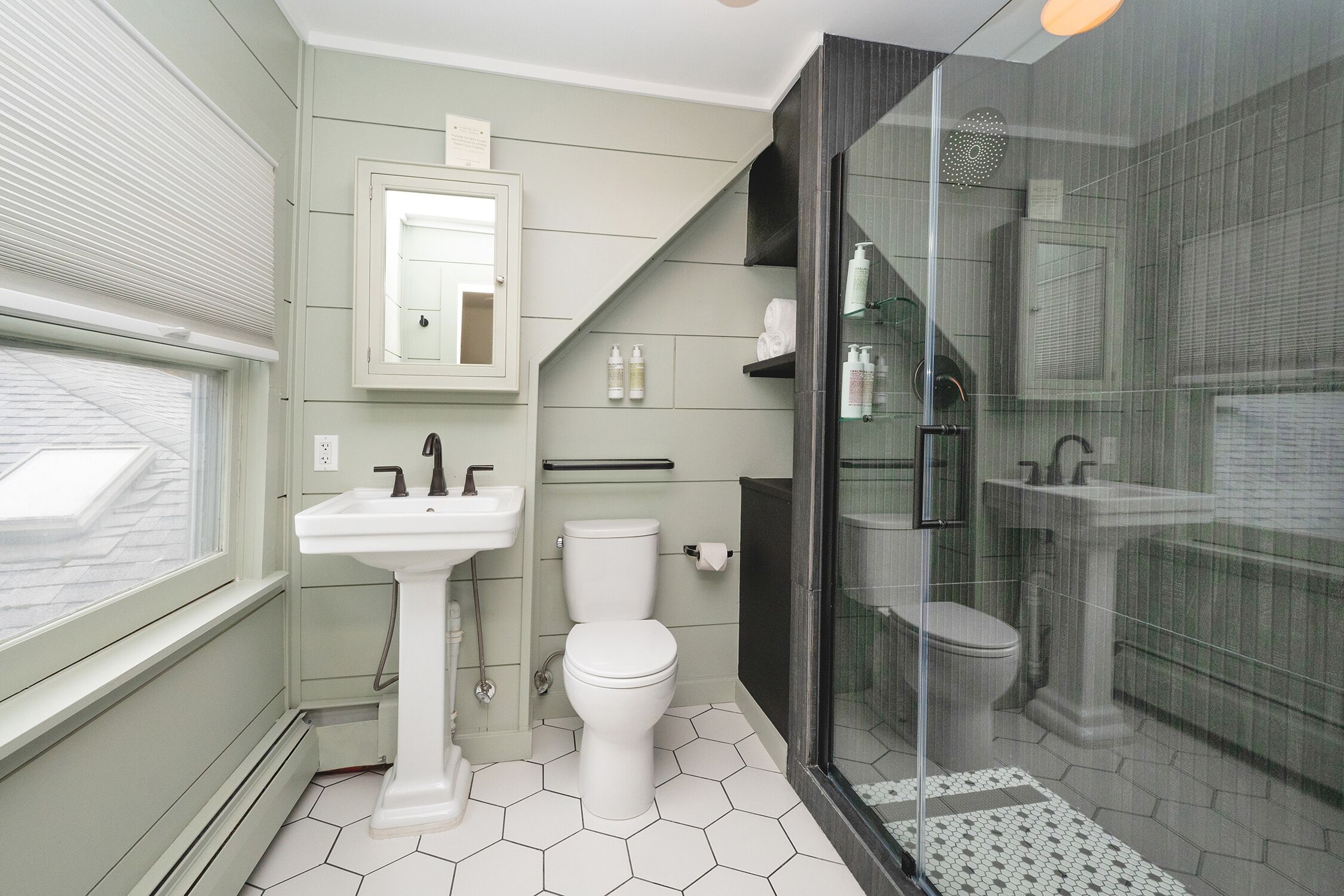 A bathroom with a white pedestal sink, a toilet, and a glass-enclosed shower area.