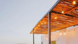 A rooftop lounge area with lounge chairs and a wooden pergola. - Hotel Mayari Holbox (Isla Holbox)