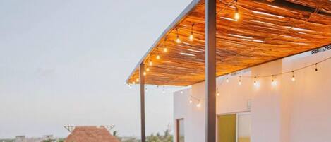 A rooftop lounge area with lounge chairs and a covered seating area.