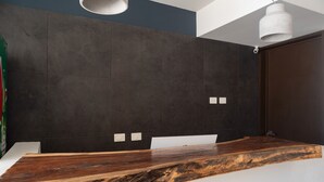 A modern bathroom with dark tiled walls, a wooden vanity, and a white ceiling light. - Hotel Mayari Holbox (Isla Holbox)