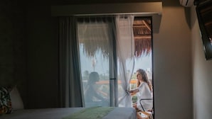 A hotel room with a bed, a window with sheer curtains, and a view of the outside. - Hotel Mayari Holbox (Isla Holbox)