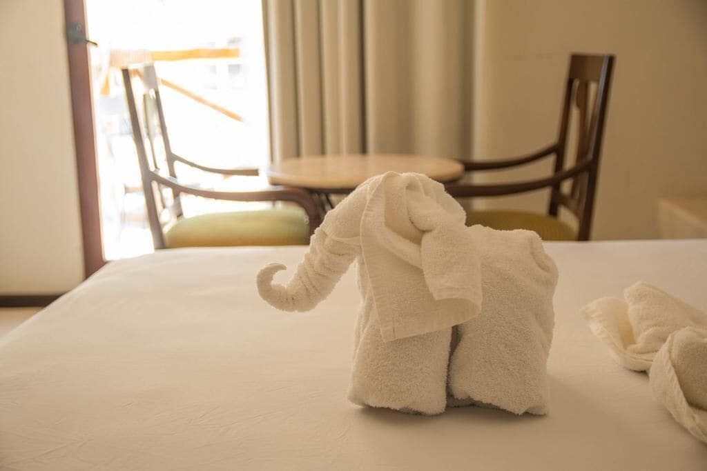 Un lit avec une couverture blanche et une serviette en forme d’éléphant.