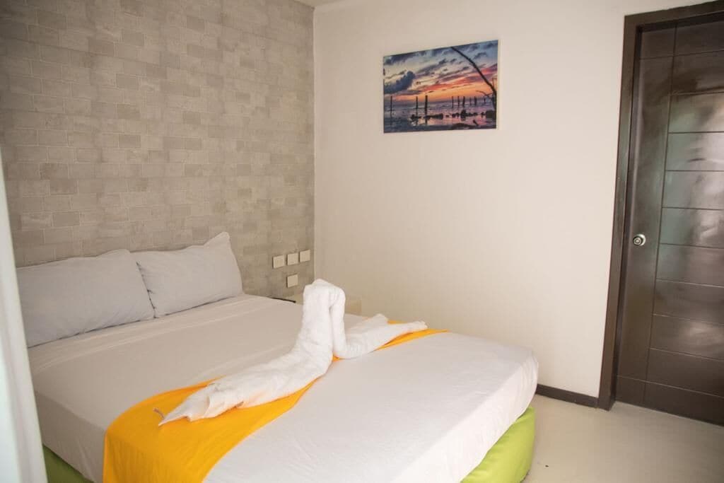 A hotel room with a bed, a painting on the wall, and a door.