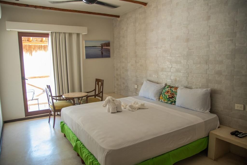 Une chambre d’hôtel avec un lit, une chaise, une petite table et une vue sur l’extérieur.
