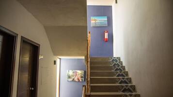 Una escalera con baldosas estampadas, un extintor de incendios fijado a la pared y dos cuadros enmarcados.