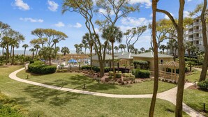 A resort with a well-maintained lawn, palm trees, and a pathway leading to a building with a balcony. - Private Balcony Overlooking Pool & Ocean (Hilton Head Island)
