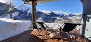 A wooden deck with two chairs and a woven basket, overlooking a snowy mountain landscape. - Charming Apartment in the Heart of Oisans (Mizoën)
