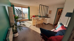 Un espacio habitable moderno con un escritorio de madera, un sofá y una planta grande en maceta.