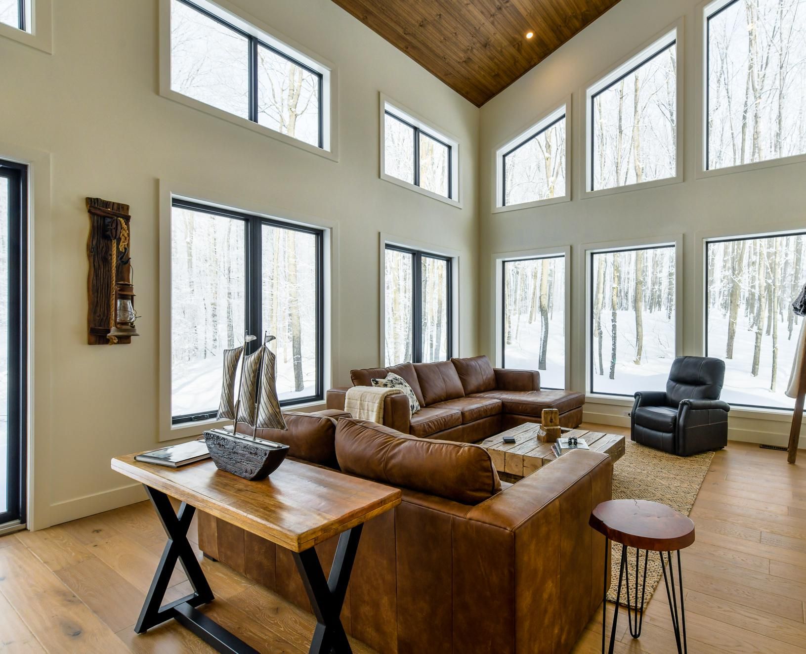 A spacious living room with large windows, a wooden ceiling, and a fireplace.