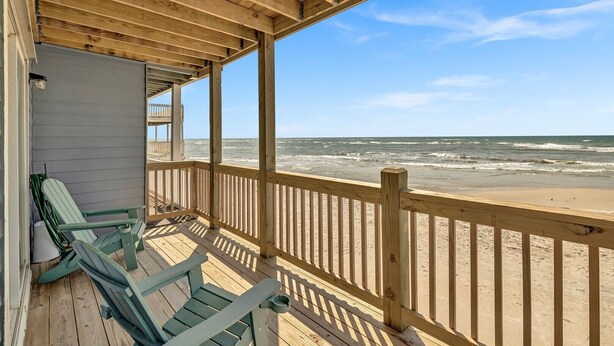 Eine Holzterrasse mit Blick auf Strand und Meer.