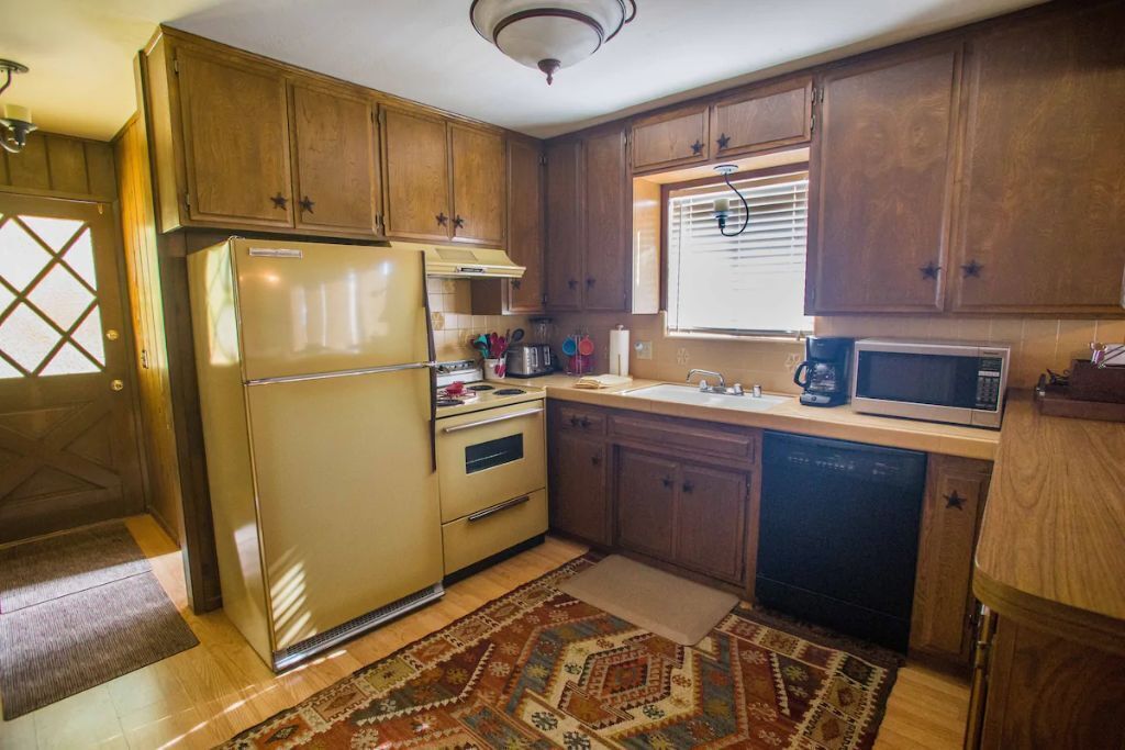 Une cuisine avec des meubles de rangement en bois, un réfrigérateur, un four à micro-ondes, un évier et une cuisinière.