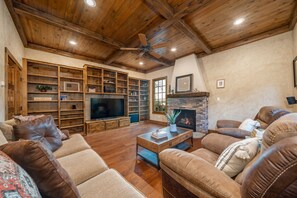 A spacious living room with a wooden ceiling, built-in shelves, a fireplace, and leather sofas. - Waterfront 5000 sq. ft. on cove, boat dock & 2 large decks, Media & Game Room. (Hot Springs Village)