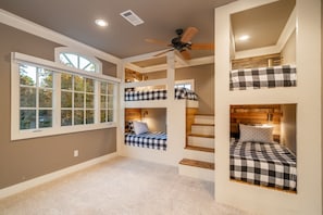 A multi-level bedroom with bunk beds, a ceiling fan, and a large window. - Waterfront 5000 sq. ft. on cove, boat dock & 2 large decks, Media & Game Room. (Hot Springs Village)