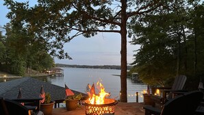 A lakeside patio with a fire pit, American flags, and Adirondack chairs. - Waterfront 5000 sq. ft. on cove, boat dock & 2 large decks, Media & Game Room. (Hot Springs Village)