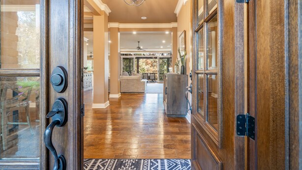 A wooden interior hallway leading to a living area with a chandelier, a sofa, and a coffee table. - Waterfront 5000 sq. ft. on cove, boat dock & 2 large decks, Media & Game Room. (Hot Springs Village)