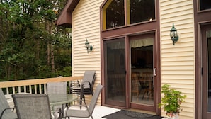 A deck with outdoor furniture, a sliding glass door, and a potted plant. - Large Cabin with WiFi. Great Location: near Castle Rock + WI Dells (Friendship)