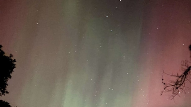 A house with large windows, surrounded by trees, under a night sky with visible stars and aurora borealis. - Large Cabin with WiFi. Great Location: near Castle Rock + WI Dells (Friendship)