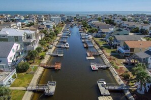 A canal lined with houses and boats, with a clear view of the waterway and surrounding residential area. - Canal Home in the heart of OIB (Ocean Isle Beach)