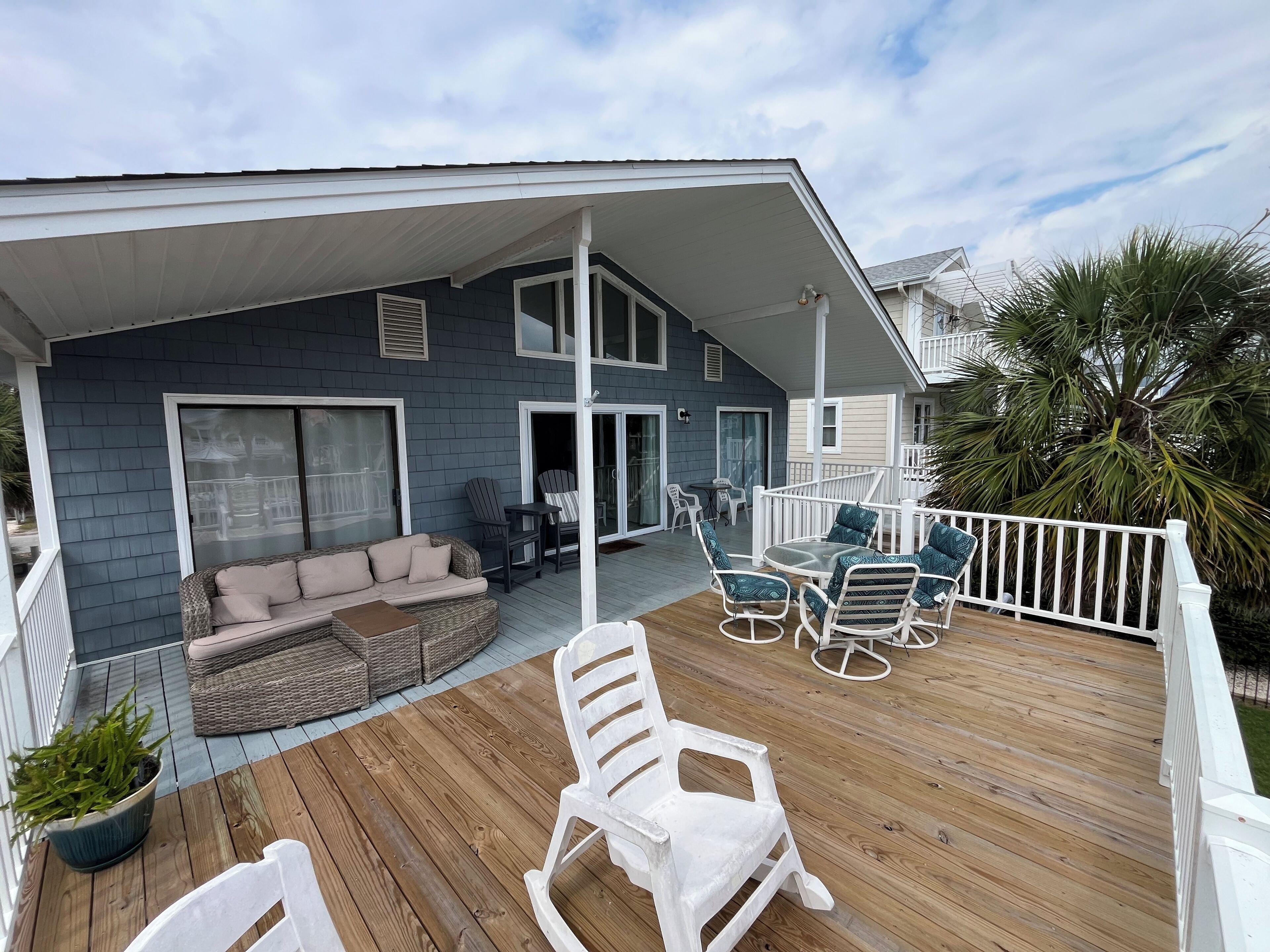 A covered outdoor deck with a sofa, chairs, and a dining table.