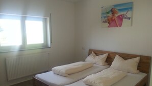 A room with two single beds, a window, a radiator, and a painting on the wall.