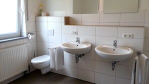 A bathroom with two sinks, a toilet, a mirror, and a window.