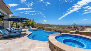 A swimming pool with two distinct sections, surrounded by stone flooring and blue lounge chairs. - Gorgeous Views, 2 Masters, 3 more En Suites (Cabo San Lucas)