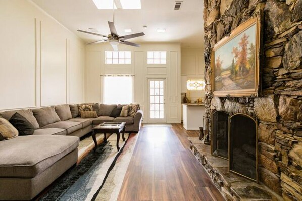 A living room with a sectional sofa, a fireplace, and a stone wall.