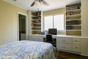 A bedroom with a bed, a desk with a computer, and bookshelves.