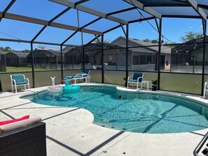A covered swimming pool with lounge chairs and a hot tub.