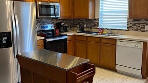 Una cocina moderna con armarios de madera, electrodomésticos de acero inoxidable y una isla central.