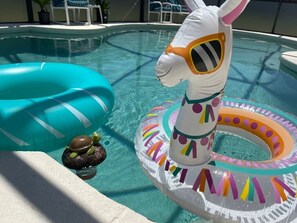 Une piscine avec des jouets gonflables, notamment un lama et une tortue.