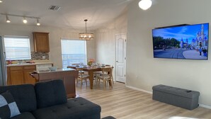 Una sala de estar moderna con un sofá modular, un reposapiés y un televisor de pantalla plana mostrando una escena de castillo.