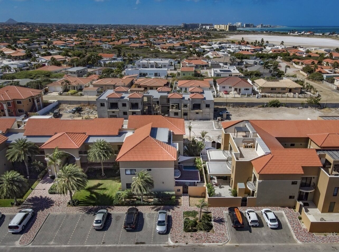 Zona residencial con varias casas, un estacionamiento y una playa al fondo.