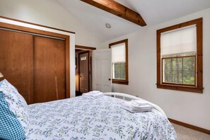 Un dormitorio con cama, armario de madera, puerta y ventana.