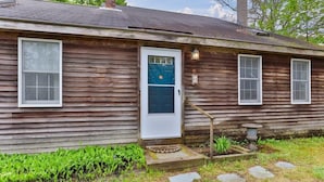 A wooden house with a white door, two windows, and a small garden area with stepping stones. - Brewster Retreat Near Bay Beaches & Dining (Brewster)