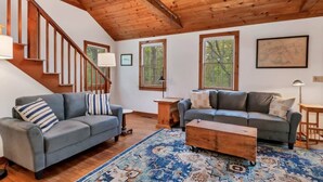 A spacious living room with a wooden staircase, two sofas, a coffee table, and a patterned rug. - Brewster Retreat Near Bay Beaches & Dining (Brewster)