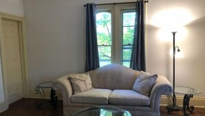 A living room with a beige sofa, a glass coffee table, and a floor lamp.