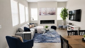 A modern living room with a sofa, coffee table, TV, and a bookshelf.