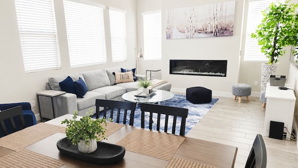Een moderne woonkamer met een bank, salontafel, eettafel en stoelen.