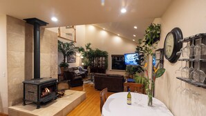 Ein gemütliches Wohnzimmer mit Kamin, bequemen Sitzgelegenheiten, einer Essecke und einem Fernseher.