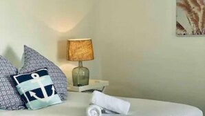 A neatly made bed with pillows, a lamp, and a painting on the wall.