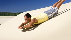 A person lying on a sand dune.
