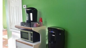 A kitchenette with a microwave, coffee maker, and water dispenser against a green wall. - 11NOLA Living In The Heart Of Many Attractions  (New Orleans)
