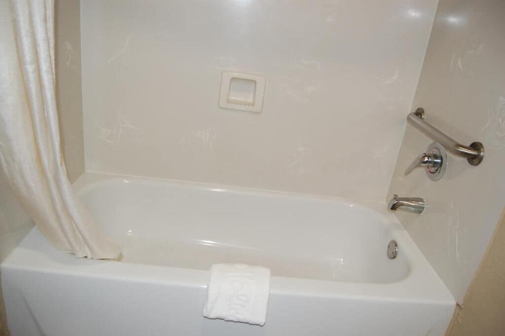 Eine weiße Badewanne mit Handtuch, Handläufe und Wasserhahn.