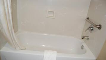 Eine weiße Badewanne mit Handtuch, Handläufe und Wasserhahn.