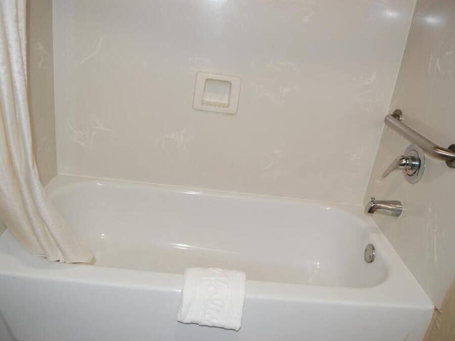 Eine weiße Badewanne mit Handtuch, Handläufe und Wasserhahn.