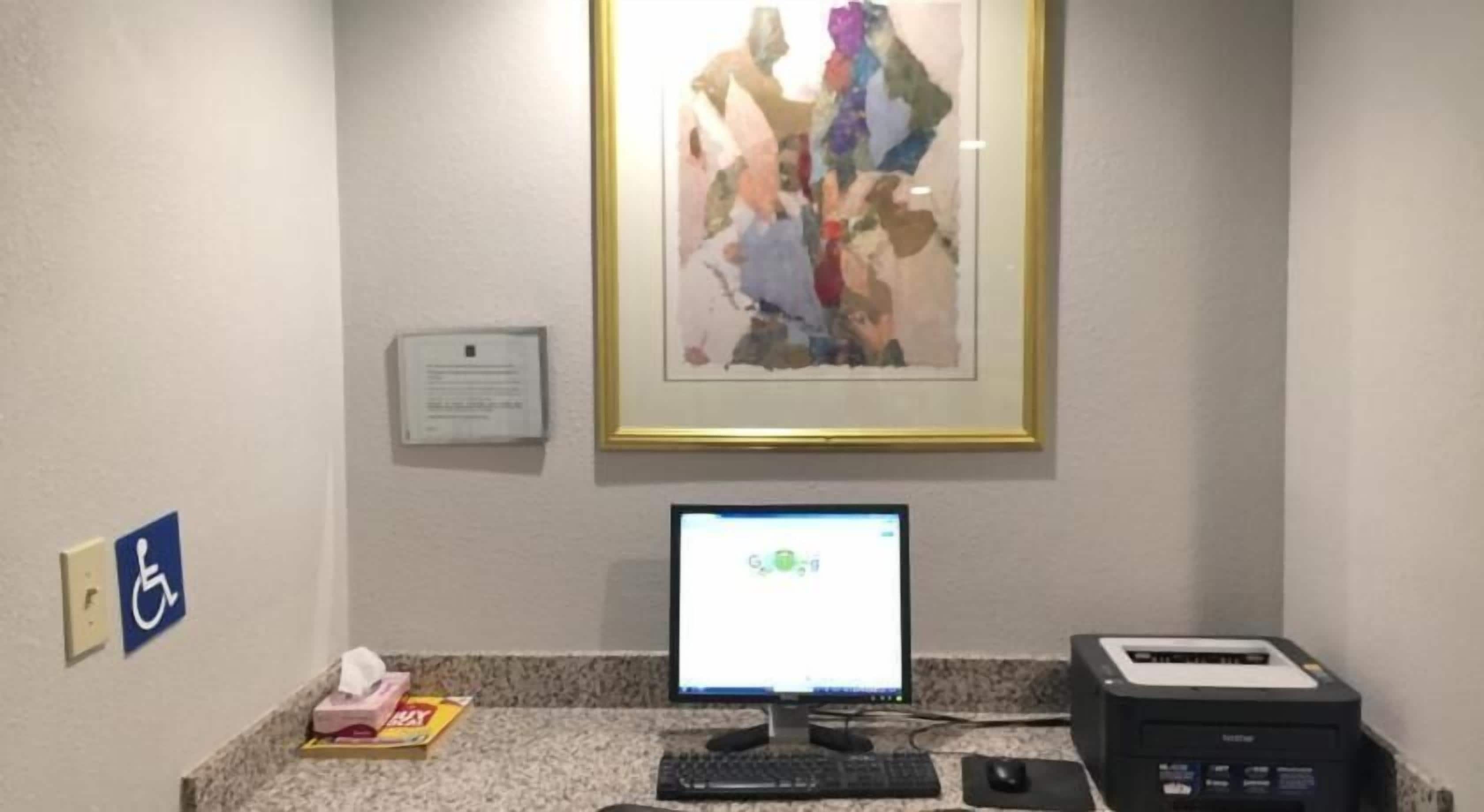 A reception area with a computer monitor, printer, and a framed abstract painting on the wall.